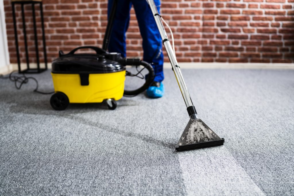 janitor vacuuming carpet in commercial office building